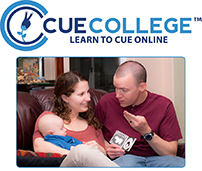 Image of Cue College advertisement. The text says "Cue College: Learn to Cue Online." There is a photograph of a white male adult with a shaved head cueing to a baby cradled in his mother's arm.