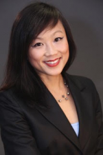 Photo of Virginia Hoang, an Asian female with long, dark brown hair. She is looking at the computer and smiling.